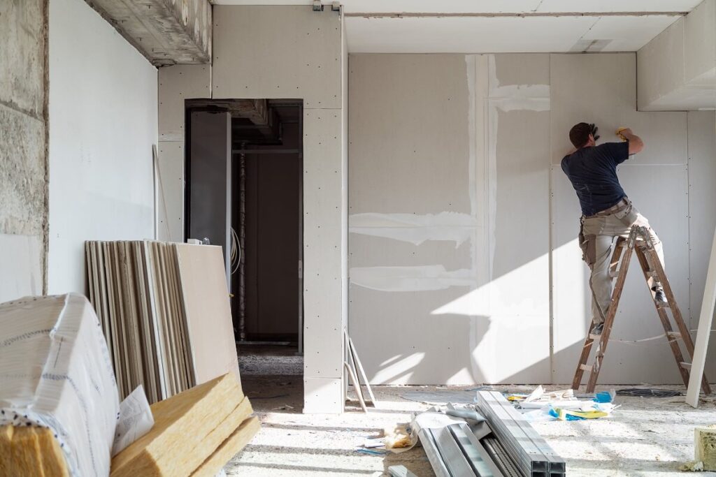 Ekipa budowlana montuje zabudowę gipsowo-kartonową, formując nowe przestrzenie wewnątrz budynku